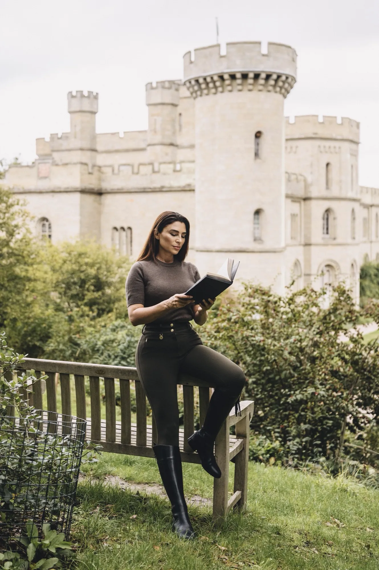 Handan Darici reading on a garden bench before a castle